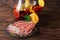 A plate of prosciutto and ham, a glass jug of beverage with apples and oranges on a wooden brown background.