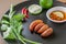 Plate of red palm weevil or Asian palm weevil larvae, fried insects with fresh vegetables and sauce in a brown dish. Eating insect