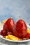 Plate with red wine poached pears and fruits on table against blue background. Space for text