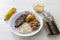 Plate of rice, beans, steak and cassava. With cutlery and manioc flour and banana for dessert.