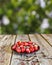 A plate of ripe strawberries a table with a place of free space with a background of a summer garden blurred in the sunlight