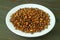 Plate of Roasted Barley for Japanese Barley Tea or Mugicha on Dark Brown Wooden Table