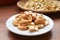 Plate of Roasted Cashew Nuts with the Uncooked in Backdrop