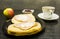 A plate with sandwiches with ham, cheese and mayonnaise. Apple and a bowl of dried cranberries, and a cup of tea.