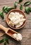 Plate and scoop with shea butter on wooden background