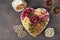 Plate shaped-heart for Valentines Day with varieties sausage, cheese, walnuts, olives and two glass rose wine on brown