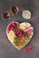 Plate shaped-heart for Valentines Day with varieties sausage, cheese, walnuts, olives and two glass rose wine on brown