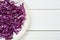 Plate with shredded fresh red cabbage on white wooden table, top view. Space for text