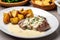 plate of sizzling steak, topped with rich creamy garlic sauce and paired with roasted potatoes