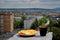 A plate with sliced â€‹â€‹orange and lemon and a mug of black tea on the background of a blurred panorama of the morning city.