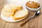 Plate with slices of bread, spoon, blue bowl with peanut butter on table