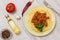 Plate with spaghetti bolognese and vegetables, spices for cooking on wooden board