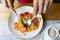 A plate of spaghetti in tomato sauce. Female hands with a knife and fork. Appetizing Italian dish. Close-up. Top view