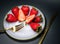 a plate of strawberries with a gold fork sitting on a table