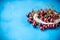 Plate with sweet cherries closeup. Freshly harvested summer berry on blue background. Vitamin containing ripe fruits