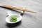 Plate with swirl of wasabi paste and chopsticks on grey table