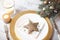 Plate and table accessories decorated with brilliant Christmas star, Christmas holiday paraphernalia and branches of spruce tree.