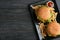 Plate with tasty burgers, french fries and sauce on wooden background, top view.