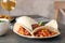 Plate with tasty chili con carne served in tortillas on table