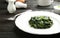 Plate with tasty cooked spinach on black wooden table, closeup.