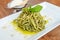 Plate of tasty pesto pasta decorated with a basil
