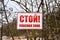 A plate with the text in Russian: Stop! Exclusion zone! Banner on barbed wire in dangerous and protected area. Stop forbidden sign