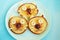 A plate with three pancakes in the shape of cat faces, decorated with slices of banana, grape and apple. Children`s food