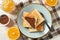 Plate with toasts, orange, choco cream and towel on wood background, top view