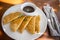 Plate with traditional quesadillas and cup of beans on brown table