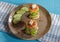 Plate with two mini pancake sandwiches with lettuce, cucumber and cheese on a checkered napkin, top view