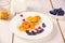 Plate of two pancakes in the shape of heart with berries on white table