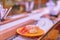 Plate of two pieces of tempura shrimps sushi on a conveyor belt.