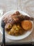 A plate of typical carribean tasty cuisine fried dumpling, rice and peas and spicy jerk chicken