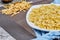 A plate of uncooked pastas with blue tablecloth on marble table