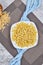 A plate of uncooked pastas with blue tablecloth on marble table