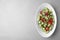 Plate of vegetarian salad with cucumber, tomato and onion on light background. Space for text
