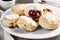 plate of warm scones, topped with scoop of strawberry jam and a dusting of powdered sugar