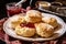 plate of warm scones, topped with scoop of strawberry jam and a dusting of powdered sugar