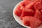 Plate of watermelon chunks on a gray mottled table side view