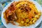 Plate of yellow rice topped with mutton meat and potatoes