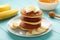 Plate with yummy banana pancakes on blue background