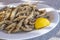 Plateful of Battered and Fried Smelts Served with a Wedge of Lemon Closeup