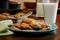 Plateful of chocolate chip cookies fresh and warm out of the oven with cold glass of milk