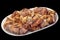 Plateful of Freshly Spit Roasted Pork Thigh Crispy Crackling Meat Slices on Oval Porcelain Tray Isolated on Black Background