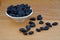 Plateful of Organic Black raisins and Spilled Black raisins on Wooden Background