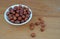 Plateful of Organic unpeeled hazelnuts and Spilled unpeeled hazelnuts on Wooden Background