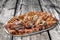 Plateful of Spit Roasted Pork Slices on Old Weathered Cracked Wooden Picnic Table