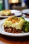 A plateof fresh baked cottage Shepherd's traditional pie with vegetables on a restaurant table