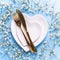 Plates in form of hearts, golden knife and fork and fresh white gypsofila flowers