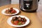 Plates with meat and garnish prepared in multi cooker